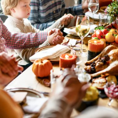 family prays around Thanksgiving table