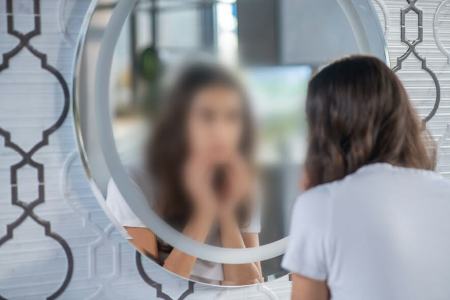 woman looking in mirror. In grief and loss of identity, Who am I after loss? is a central question. While roles change, knowing our identity in Christ secures us.